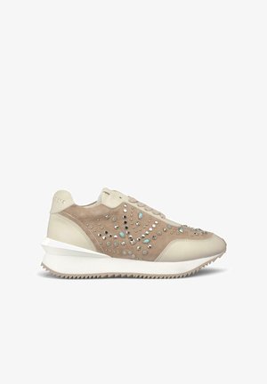Beige suede and leather sneakers featuring studded embellishments, a textured upper, and a white, patterned rubber sole.