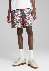 Pantaloni corti con una stampa colorata su tutta la superficie, caratterizzati da branding e numeri, realizzati in tessuto leggero. Abbinati a calzini bianchi e sneakers.