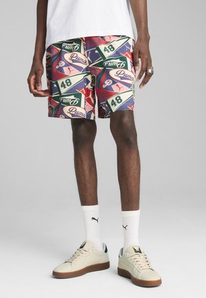 Shorts med et farverigt all-over tryk, der har branding og tal, lavet af letvægtsstof. Parret med hvide sokker og sneakers.