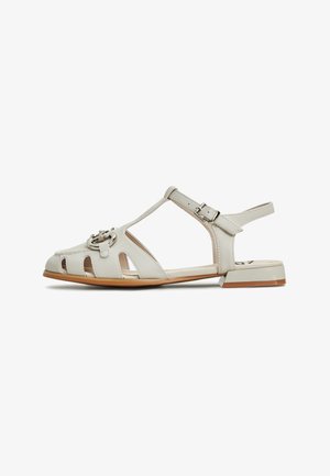 Sandale blanche en cuir avec bout ouvert et découpes sur le côté. Dotée d'une bride de cheville réglable et d'un détail de boucle métallique. Talon block bas.