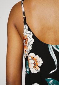 Black floral dress featuring bright orange and white flowers, adjustable straps, and a smooth fabric texture. The design includes leafy accents.