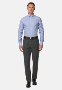 Gaiši zils un balts svītrainais krekls ar tumši pelēkām svinīgām biksēm un melniem apaviem, ar standarta apkakli un garām piedurknēm.