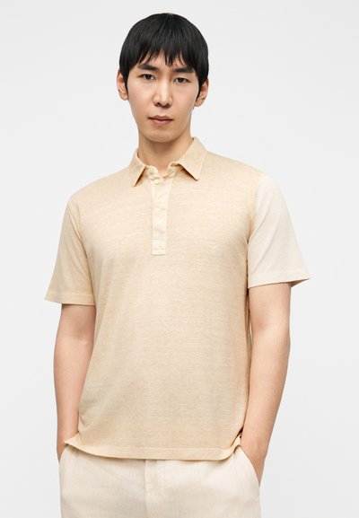 Μπεζ πόλο πουκάμισο με κουμπωτή λωρίδα, κοντά μανίκια και υφασμάτινη υφή. Το ύφασμα είναι απαλό με διακριτικό μοτίβο heather.