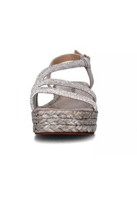 Sandalo con zeppa grigia chiara, suola in juta intrecciata, cinturini a incrocio decorati e fibbia regolabile alla caviglia. Parte superiore morbida e texturizzata.