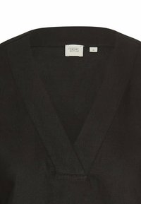 Sort V-hals skjorte lavet af blødt stof, med et minimalistisk design med rene linjer og et mærke med teksten "camel active" i størrelse S.