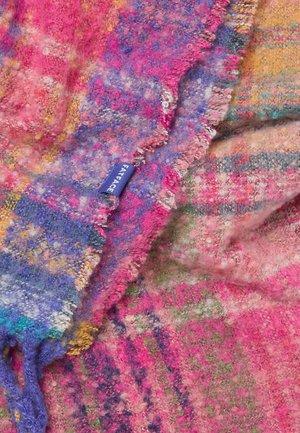 Mehrfarbiges Karomuster-Decke in Rosa, Lila und Gelb mit einer weichen, strukturierten Oberfläche und einem Fransenrand, ausgestattet mit einem blauen Stofflabel.