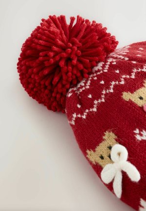 Rote Strickmütze mit einem großen roten Pom-Pom, weißen Herzmustern und Bärenköpfen mit weißen Schleifen. Weicher Textur und festliches Design.