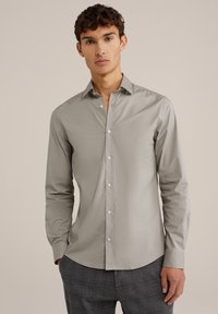 Chemise boutonnée gris clair à manches longues, coupe ajustée et texture lisse. Caractéristiques d'un col cranté et de boutons blancs.