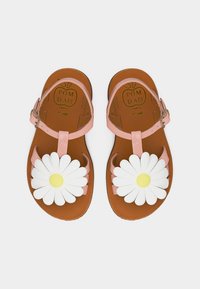 Sandales en cuir rose pour enfants avec brides à la cheville et grandes décorations de marguerites blanches sur semelles marron.
