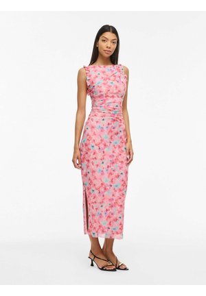 Karcsúsított, ujjatlan rózsaszín virágos midi ruha oldalsó sliccel, fekete alacsony sarkú szandállal viselve, fehér háttér előtt álló nőn.