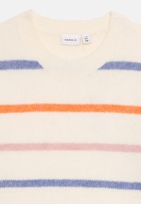 Pull en tricot à col rond de couleur crème avec des rayures horizontales en lavande, orange et rose. Texture douce, col côtelé, et étiquette de marque visible.