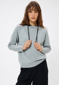 Grå sweatshirt med rund halsudskæring, sort snor og ribbede manchetter. Letvægtsstof med en afslappet pasform, kombineret med sorte bukser.