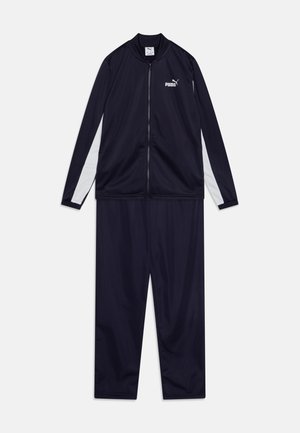 Marine atletisk treningsdrakt laget av glatt, lett stoff. Den har en jakke med glidelås som har hvite side-striper og logo, samt matchende bukser.