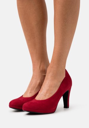 Escarpins en daim rouge avec un bout arrondi et un talon aiguille noir de 10 cm ; texture douce et design élégant, adaptés à une tenue formelle.