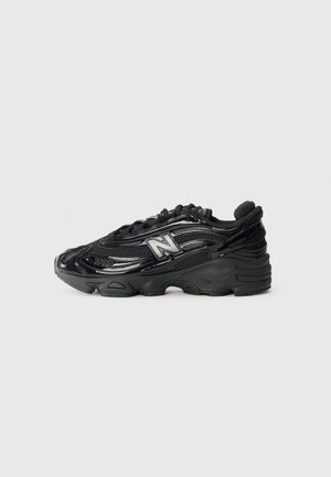 Baskets noires New Balance avec des détails brillants, logo "N" sur le côté, semelle épaisse et fermeture à lacets, montrées de profil sur fond clair.