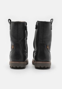 Svarta läderankelboots med en texturerad finish, med en brun gummisula och en logodetalj på sidan. Dragkedjestängning på baksidan.