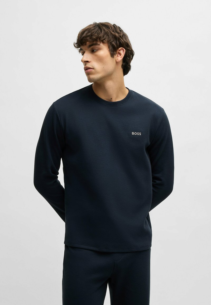 Donkerblauwe lange mouwen T-shirt van textuurstof, met een ronde hals en een klein wit "BOSS" logo op de borst.