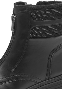 Bottine en cuir noir avec fermeture à glissière, panneau texturé avec petits clous, et doublure intérieure douce. Finition lisse et semelle robuste.