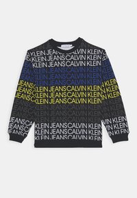 Sudadera negra con un patrón de texto multicolor que presenta "CALVIN KLEIN JEANS." Cuello redondo, mangas largas, puños y dobladillo acanalados.