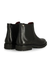 Botas de tobillo de cuero negro con paneles laterales elásticos, punta redonda, suela de goma duradera y un discreto detalle de logo metálico cerca del talón.