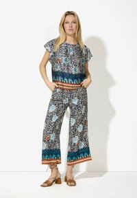 Musterhaftes Zweiteiler-Outfit mit kurzärmeligem Oberteil und weit geschnittenen Hosen. Es zeichnet sich durch ein blaues Blumenmuster auf navy Hintergrund sowie braune und türkisfarbene Akzente aus.