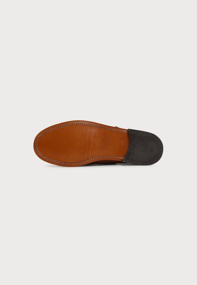 Chaussure habillée pour homme à semelle en cuir vue par en dessous, montrant une semelle marron aux bords cousus et un talon noir.