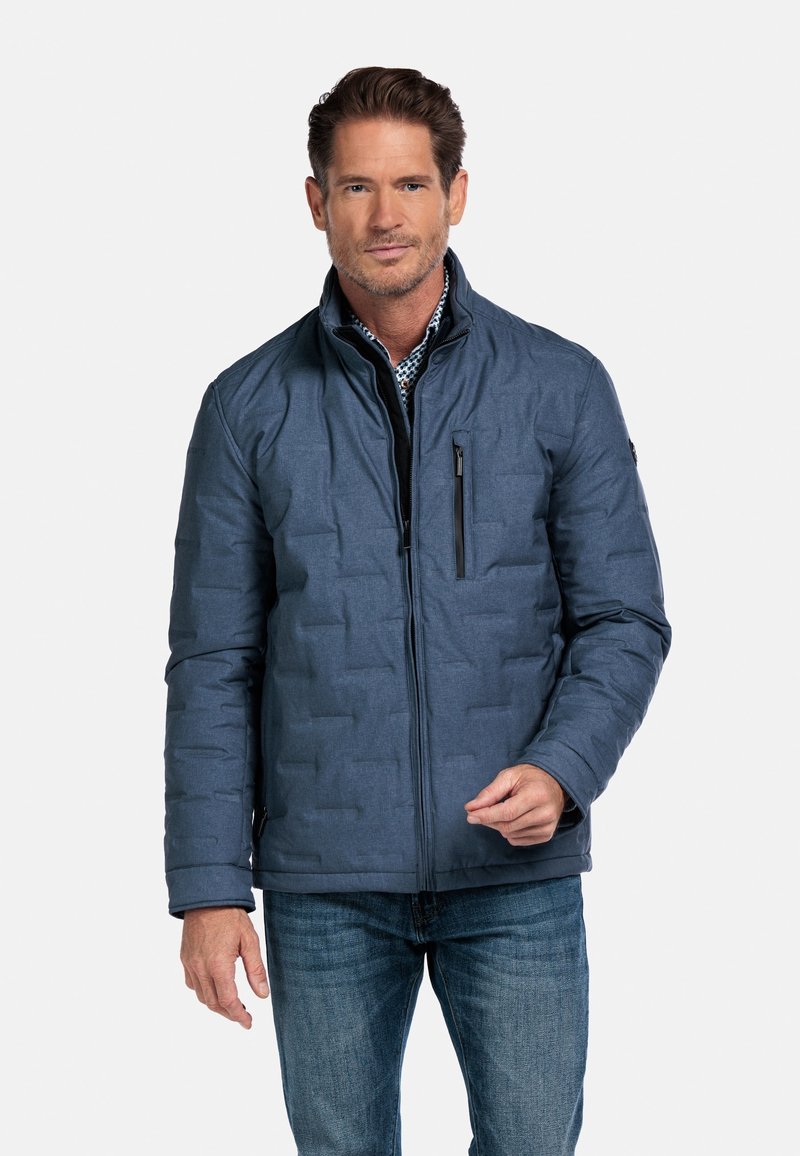 Mannelijke gewatteerde jas in donkerblauw, gemaakt van gestructureerde stof. Voorzien van een ritssluiting aan de voorkant, een ritszak op de borst en een staande kraag.