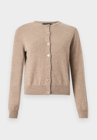 Beige vestje gemaakt van zachte stof; heeft een ronde hals en mouwen over de volle lengte. Zeven sierknopen aan de voorkant verfraaien het ontwerp.