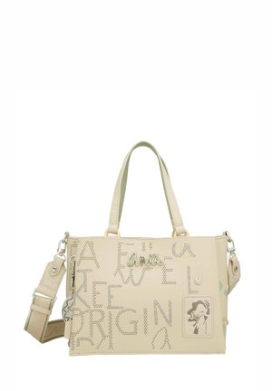 Bolso de mano de cuero sintético color beige con texto recortado, logo metálico y acentos decorativos. Cuenta con dos asas y una correa de hombro removible.