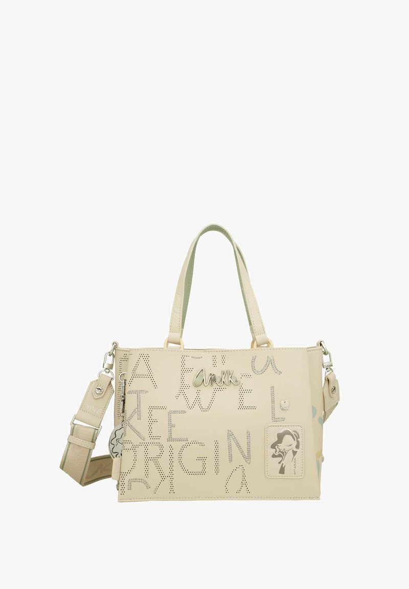 Bolso de mano de cuero sintético color beige con texto recortado, logo metálico y acentos decorativos. Cuenta con dos asas y una correa de hombro removible.