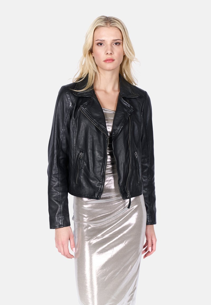 Zwart leren bikerjack met ritsen, cropped ontwerp, pieklapels en textuurafwerking. Draagt over een metallic zilveren jurk.