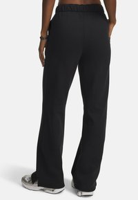 Un pantalon de survêtement noir avec une taille élastique et une coupe décontractée. Fabriqué à partir d'un matériau doux avec des coutures latérales et une légère élasticité.