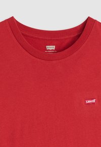 Rød bomull t-skjorte med rund hals og en liten, brodert Levi's-logo på venstre bryst. Glatt tekstur, avslappet passform.