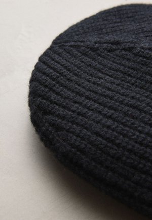 Berretto basco scuro lavorato a maglia con trama a coste, realizzato in lana, caratterizzato da una forma ovale e da un tessuto spesso e morbido. Nessuna decorazione o disegno visibile.