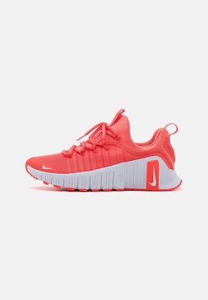 Baskets de sport rouge corail avec semelle blanche épaisse, lacets et logos Nike sur la pointe et le talon, présentées en profil sur fond blanc.