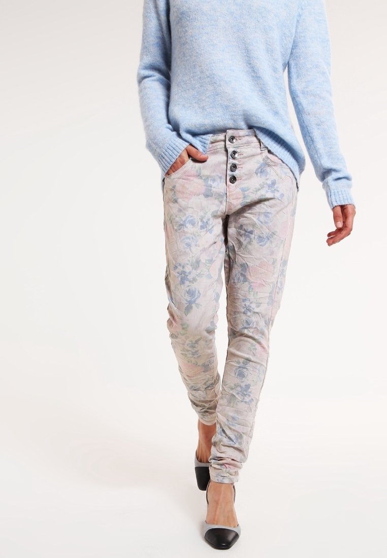 Ljusblå tröja i kombination med trånga byxor med blommönster i ljusa nyanser, med femknappsdetalj och fickor; svartvita klackskor.