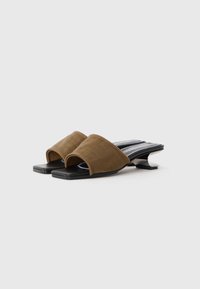Brown fabric slide sandals with an open toe design, black flat sole, and distinctive curved heel. Textured upper with a smooth lining.