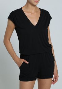 Zwarte short-sleeve romper met V-hals, zachte textuur, elastische taille, zijzakken en aansluitende mouwen.