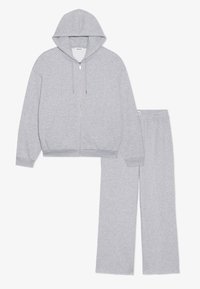 Hall halliga kapuutsiga dressipluus, millel on ees lukk ja küljetaskud, koos sobivate hallide dressipükstega, millel on elastne vöökoht.