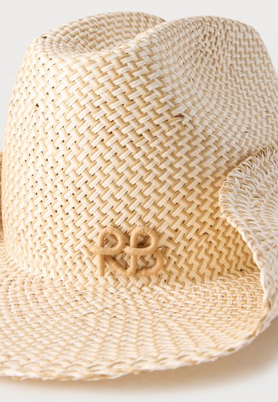 Ανοιχτό μπεζ υφαντό ψάθινο καπέλο fedora με διακοσμητικό υφαντό μονογράμμα "RB" στο μπροστινό μέρος της κορυφής.