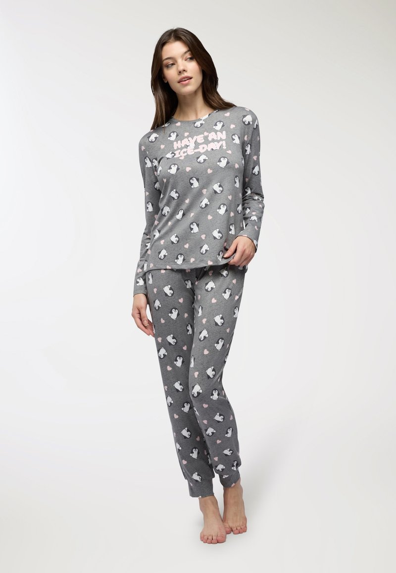 Completo pigiama grigio composto da una maglia a maniche lunghe con una grafica di pinguino e testo, e pantaloni con un motivo di pinguini e cuori. Materiale in misto cotone.