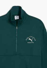 Donkergroene fleecejack met een hoge kraag, halve rits en een lichtbeige "PUMA ATHLETICS" logo met een springende poema-ontwerp.