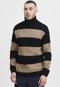 Svart og beige stripete genser med høy hals, ribbet tekstur og lange ermer, med brede horisontale striper.