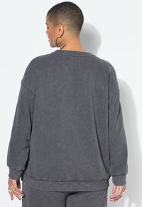 Overmaatse grijze sweatshirt met een gladde textuur, geribbelde manchetten en een brede halslijn. Heeft afhangende schouders en een ontspannen silhouet.