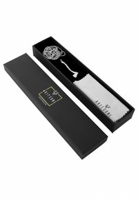 Scatola nera con logo dorato contenente una collana d'argento e un panno per la pulizia bianco. L'interno è nero, mettendo in risalto i gioielli.