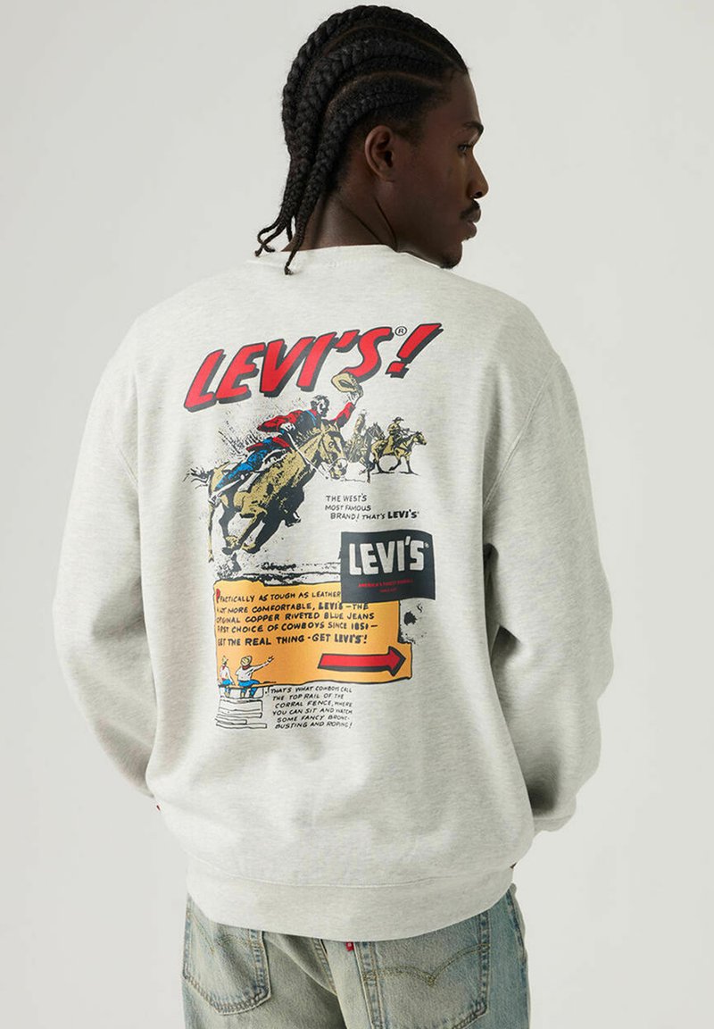 Sweat-shirt gris en coton avec un imprimé graphique coloré au dos. Le texte inclut le nom de la marque "Levi's !" et des illustrations de cow-boys.