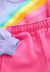 Violeta krekls ar varavīksnes svītrām; rozā, elastīgas sporta bikses ar elastīgu jostu. Mīksta, teksturēta auduma.