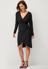Zwarte wikkeljurk met lange mouwen, V-hals en asymmetrische zoom. Gemaakt van een gladde stof met een slim fit ontwerp en minimale details.