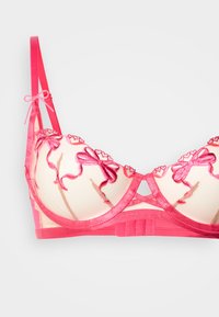 Rosa blonde-BH med blomsterbroderi og sløyfedetalj. Gjennomsiktige mesh-kopper med forsterkede stropper og bredt bånd for støtte. Jevn tekstur.