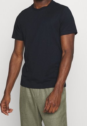 Sort bomulds t-shirt med rund hals og korte ærmer, med en tætsiddende pasform og glat tekstur. Bæres med lysegrønne teksturerede bukser.